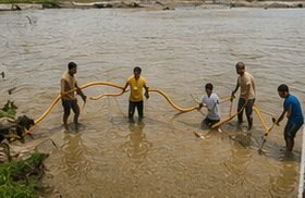 Crew standing in shallow water handling a fill line